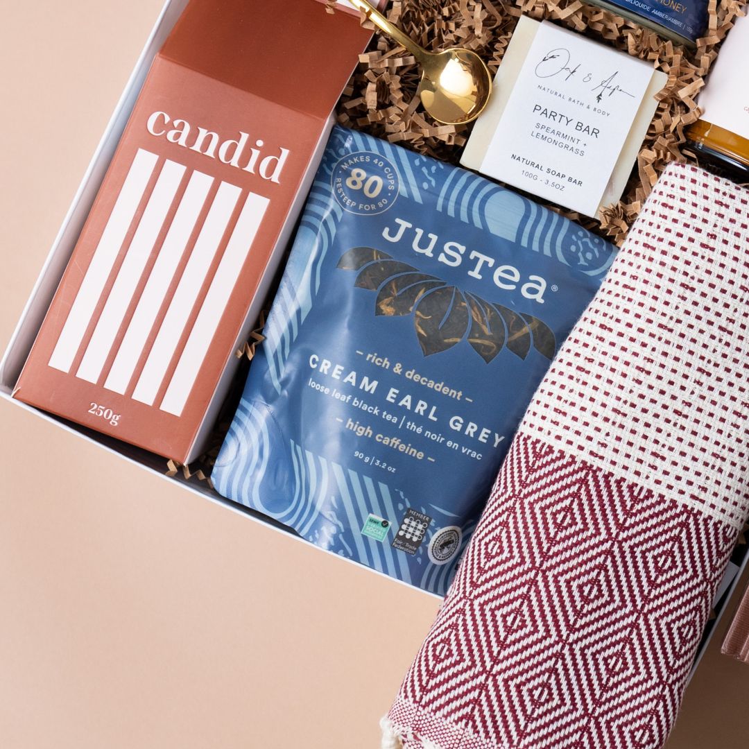 Close-up of Candid coffee, JusTea, honey, a gold spoon and a woven towel in the Call It Home gift.