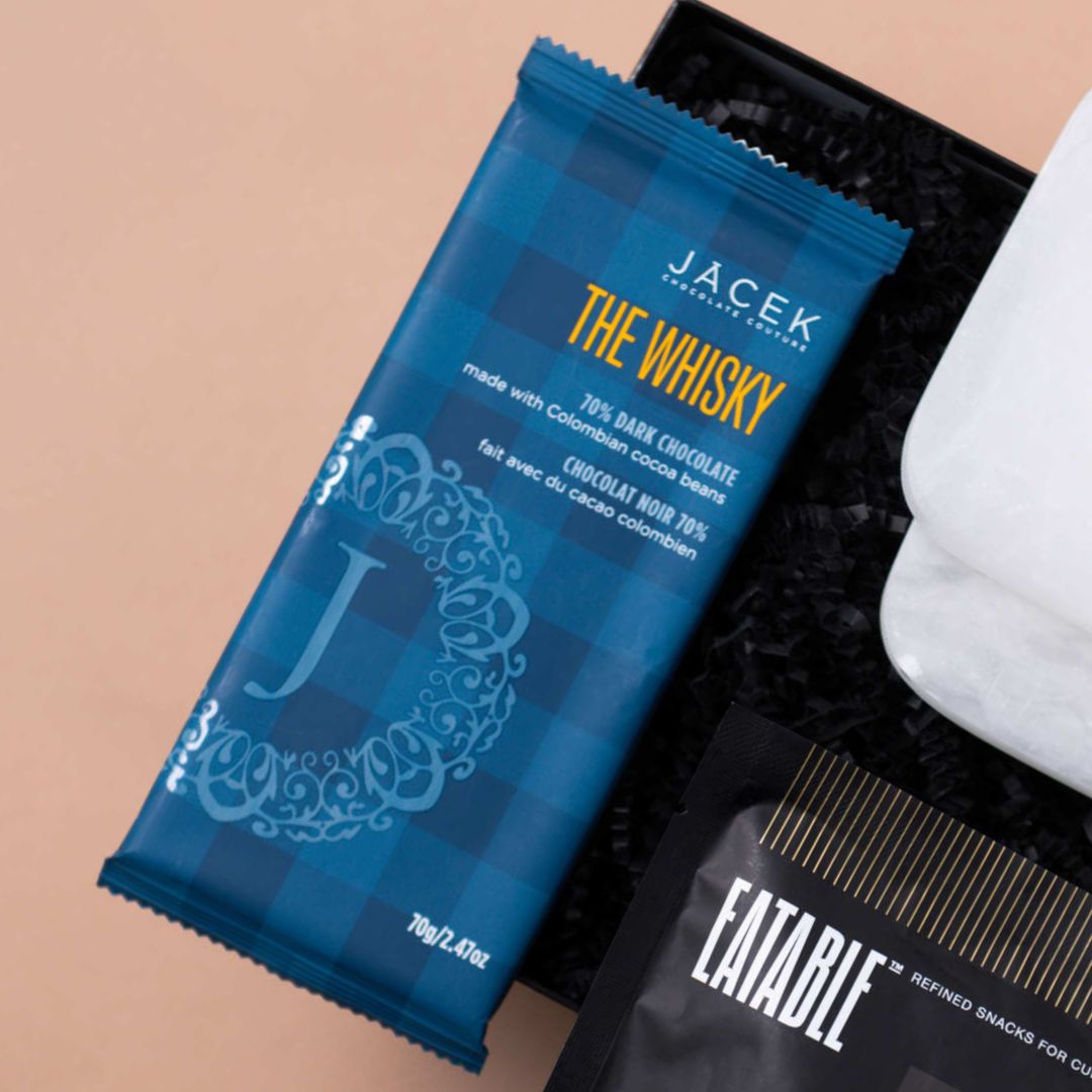 Close-up of a JACEK Whiskey Chocolate bar beside Eatable Whiskey on the Pops popcorn.